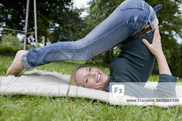 Frau streckt sich auf Decke im Gras