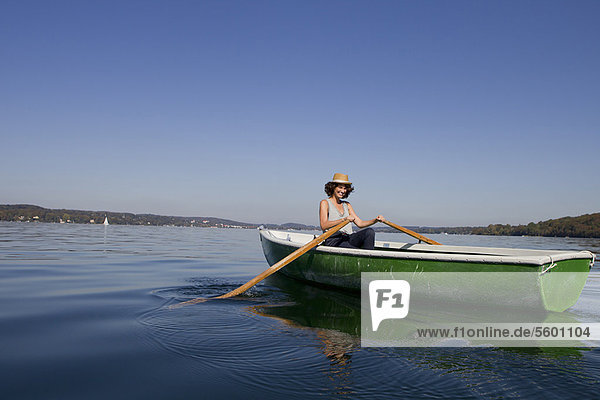 Woman rowing boat in still lake