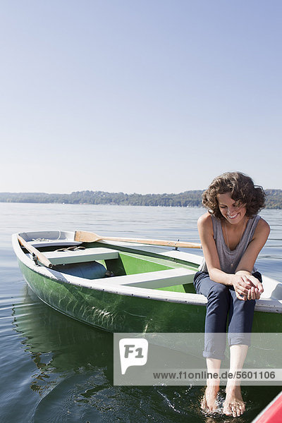 Woman dangling feet from boat in lake