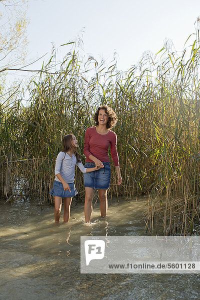 Mother and daughter walking in pond
