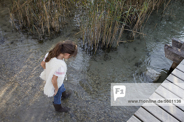 Mädchen in Stiefeln beim Spaziergang im Teich