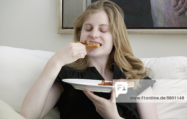 Teenage girl eating on sofa