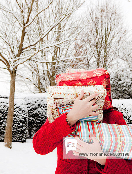 Frau mit verpackten Geschenken im Schnee