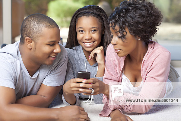 Smiling family using cell phone together