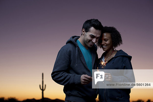 Couple playing with sparklers in desert