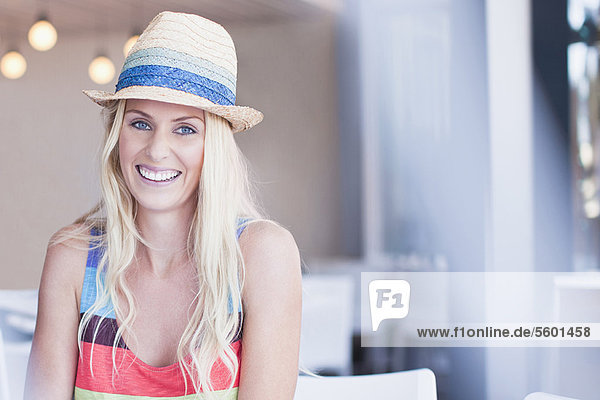 Smiling woman in sunhat sitting in cafe