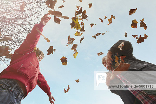 Kinder spielen mit Herbstblättern