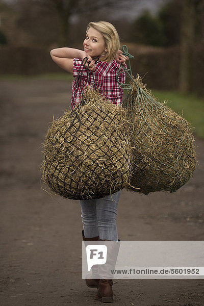 Teenage girl carrying hay on dirt path
