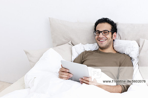 Man using tablet computer in bed