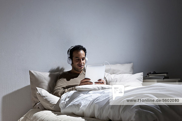 Man using tablet computer in bed