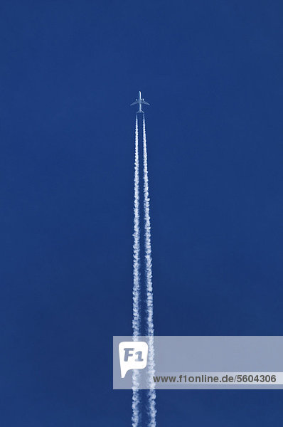 Flugzeug mit doppeltem Kondensstreifen am blauen Himmel