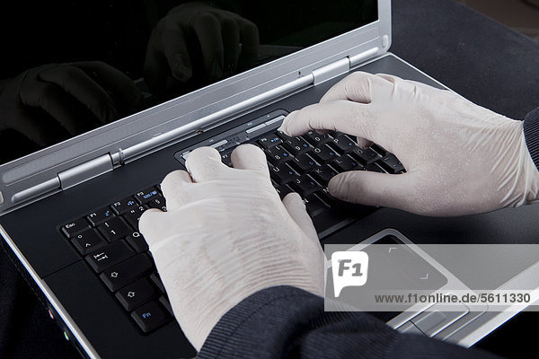 Hacker using a laptop  wearing latex gloves to leave no traces  symbolic image for Internet crime