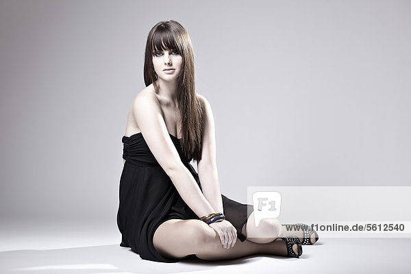 Young woman posing in black dress  sitting