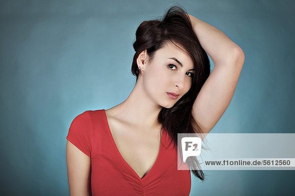 Young woman wearing red top  posing in front of blue wall