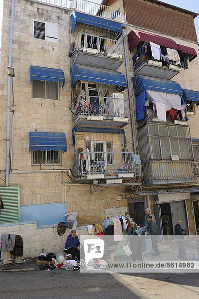 Street scene  woman selling clothes in the street  residential houses with balconies that are being used  in front of the Mahane Yehuda Market  Jerusalem  Israel  Middle East