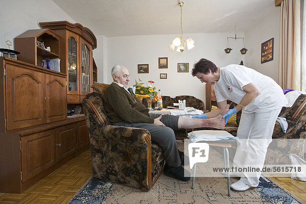 Ambulante Pflege des Deutschen Roten Kreuzes  Pflegeschwester Anke Lehmann besucht ein älteres Ehepaar  um dem Mann einen Fuß-Verband zu wechseln  Treuenbrietzen  Brandenburg  Deutschland  Europa