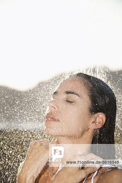 Erwachsene Frau mit geschlossenen Augen beim Duschen im Freien