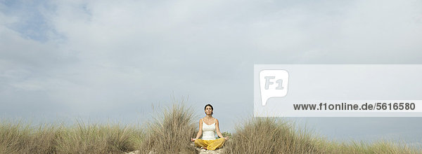 Reife Frau beim Meditieren am Strand