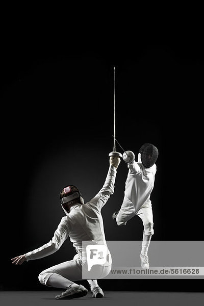 Fencers fencing  one fencer jumping in air