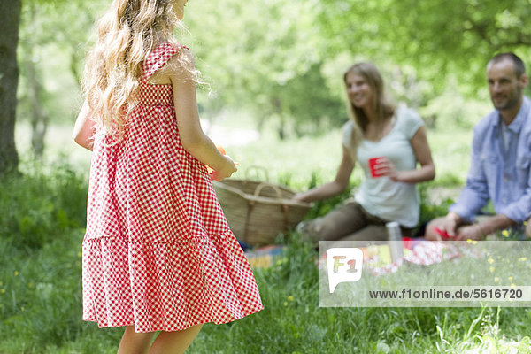 Mädchen beim Picknick mit Eltern im Freien  Rückansicht