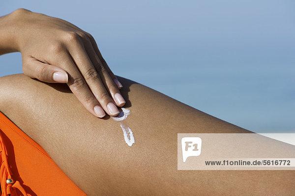 Frau mit Sonnenschutz am Strand  beschnitten