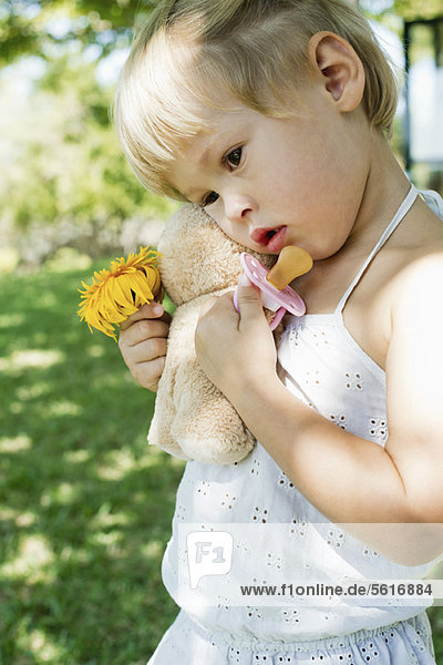 Kleines Mädchen mit Teddybär  Blume und Schnuller