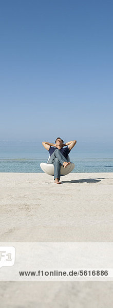Mann entspannt sich im Sessel am Strand