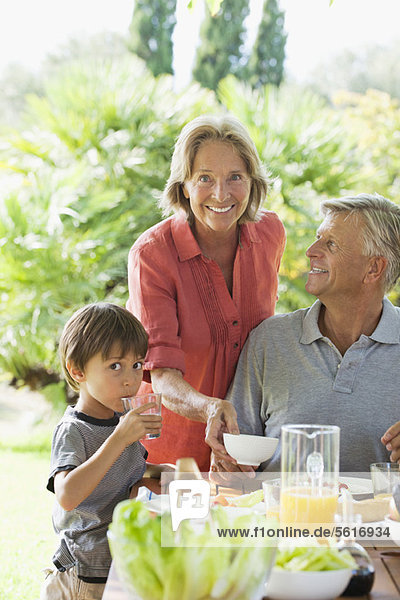 Junge und Großeltern beim Essen im Freien