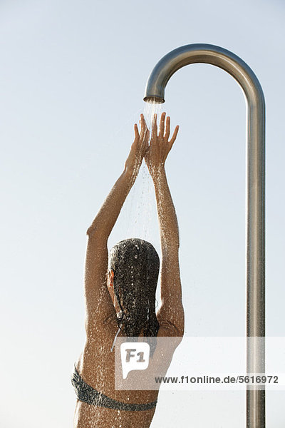 Woman in bikini top showering outdoors