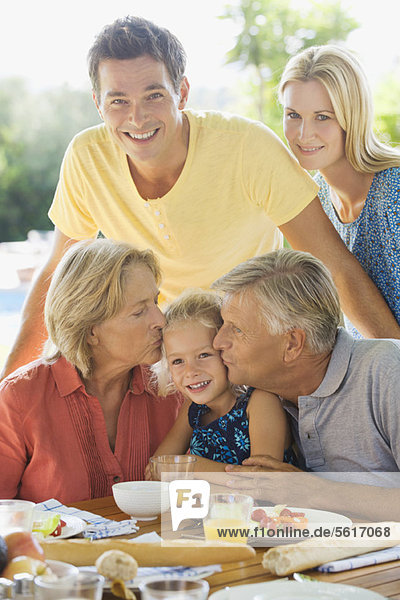 Familie beim Frühstück im Freien  Großeltern küssen die Wangen der Enkelin  Porträt