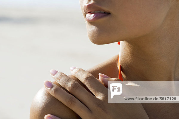 Woman touching bare shoulder at the beach  cropped