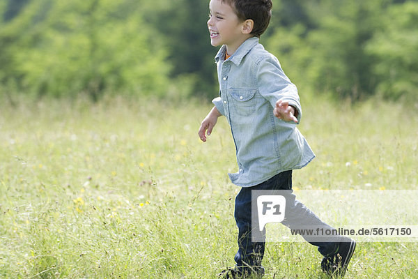 Little boy running in meadow  side view