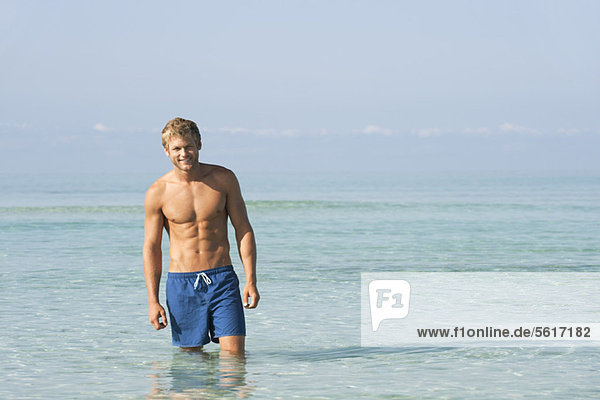 Barechested young man standing knee deep in water  portrait
