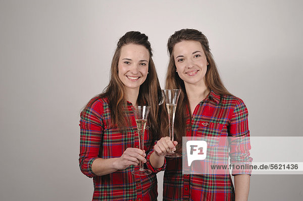 Twin sisters holding champagne glasses for a toast
