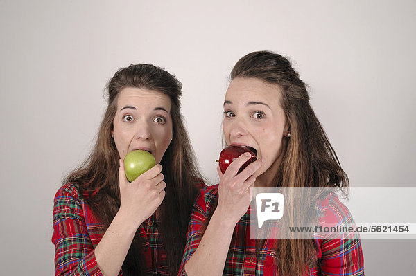 Zwillingsschwestern  die eine mit einem roten Apfel  die andere mit einem grünen