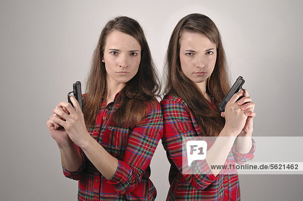 Twin sisters holding pistols