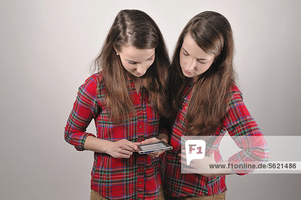 Twin sisters looking at an e-book reader