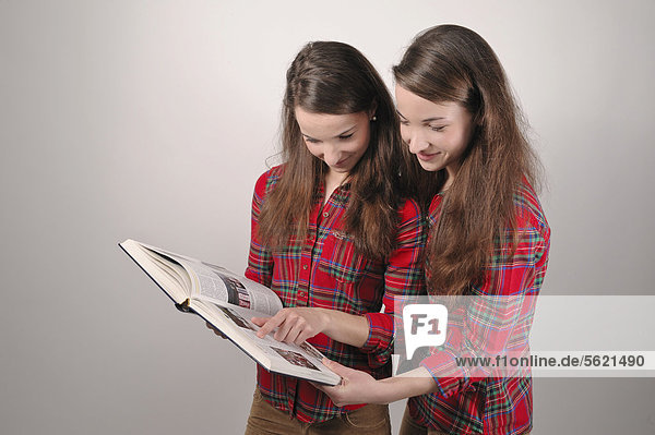 Twin sisters reading a book together