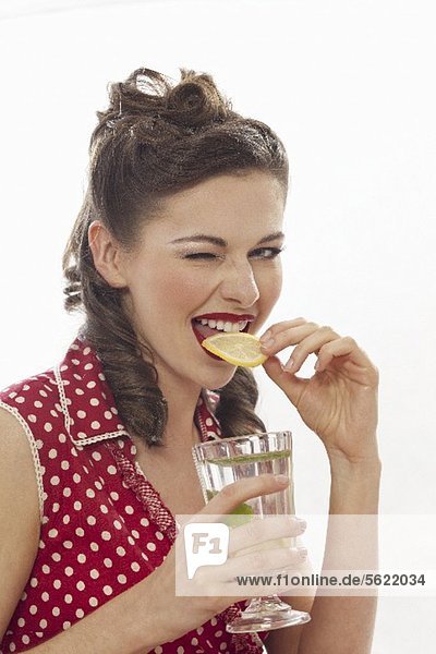 A retro-style girl eating a slice of lemon from a glass of lemonade