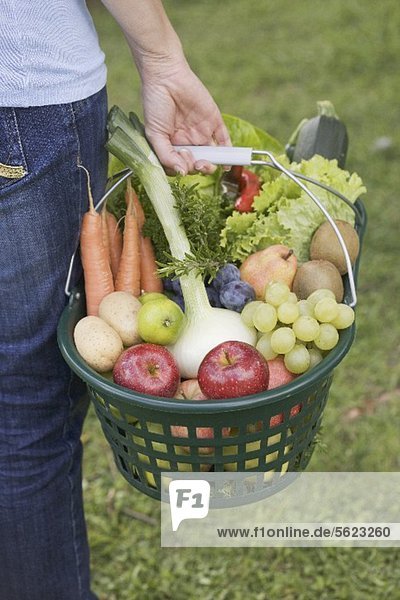Frau trägt Korb mit Obst und Gemüse