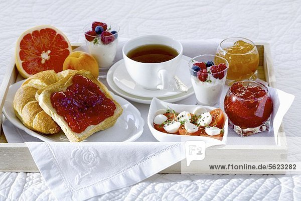 Frühstück im Bett mit Tee  Marmelade  Joghurt  Obst und Tomaten mit Mozzarella