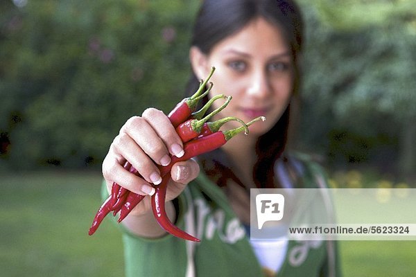 Frau hält frische rote Chilischoten