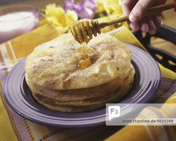 Hand Drizzling Honey Over Sopapillas (Mexican Fried Pastry)