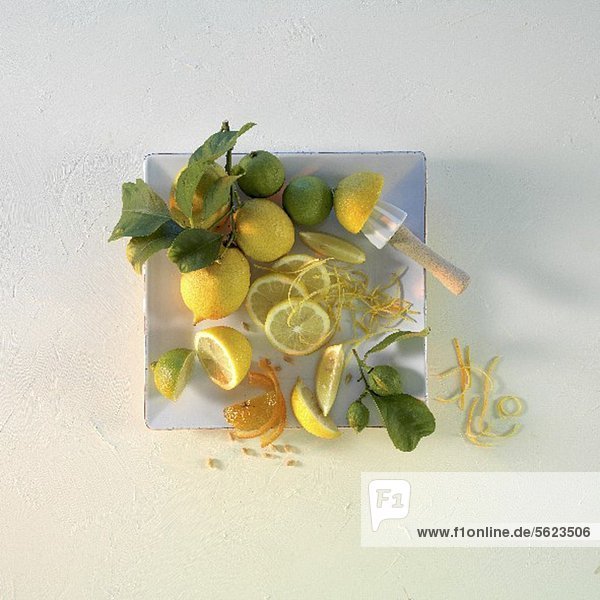 Zitronen und Limetten mit Blättern auf quadratischem Teller