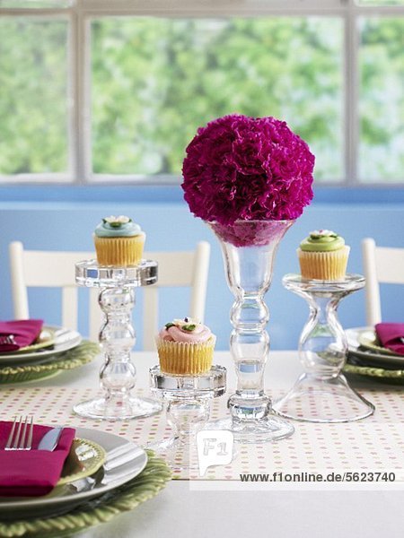 A festively laid table with flower balls and cupcakes
