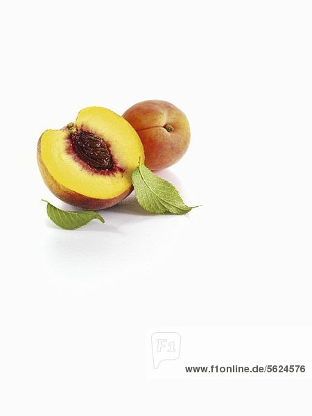Halber Pfirsich und Aprikose mit Blättern
