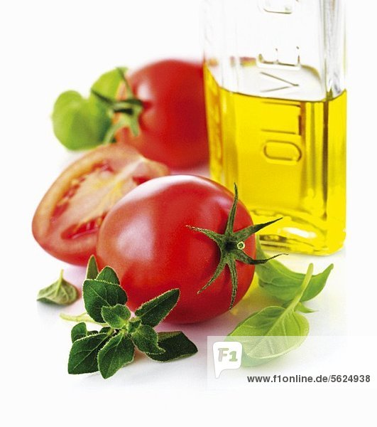 Tomaten  Olivenöl in der Flasche & frische Kräuter (Nahaufnahme)