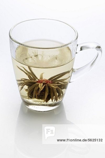 A glass of jasmine tea with a tea rose