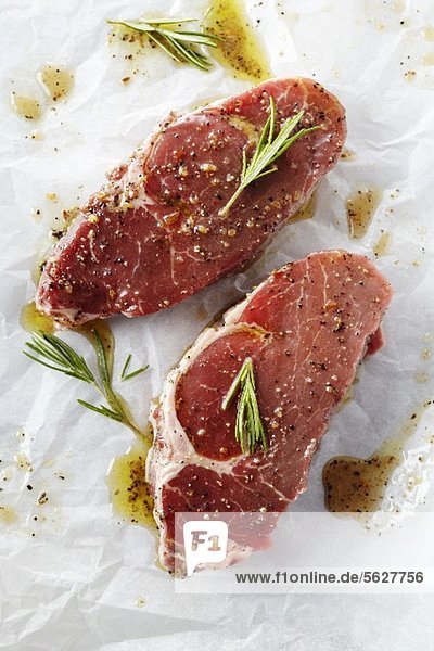Two Raw Steaks with Marinade and Rosemary on Butcher's Paper