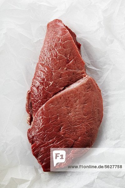 Raw beef steak on greaseproof paper